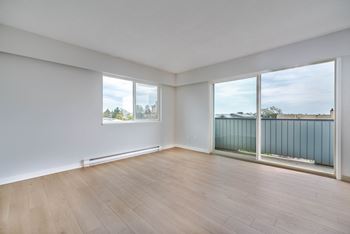 A room with wooden flooring and a balcony with glass doors.