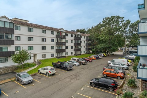 A parking lot with cars and apartment buildings in the background.