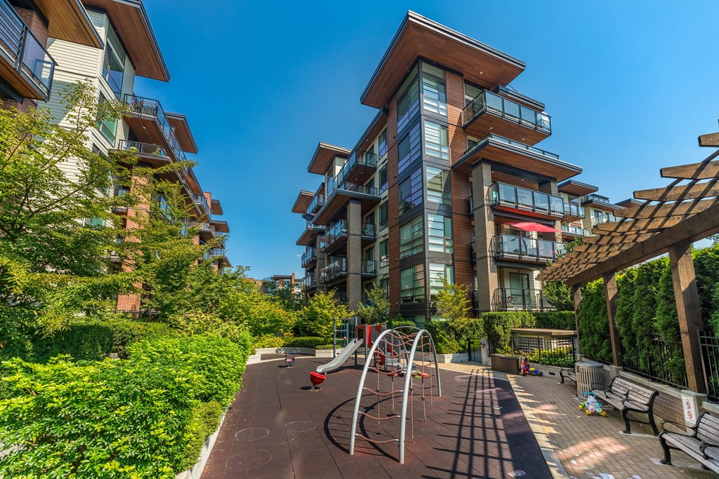 A playground with a slide and a climbing frame is situated in a courtyard surrounded by residential buildings.