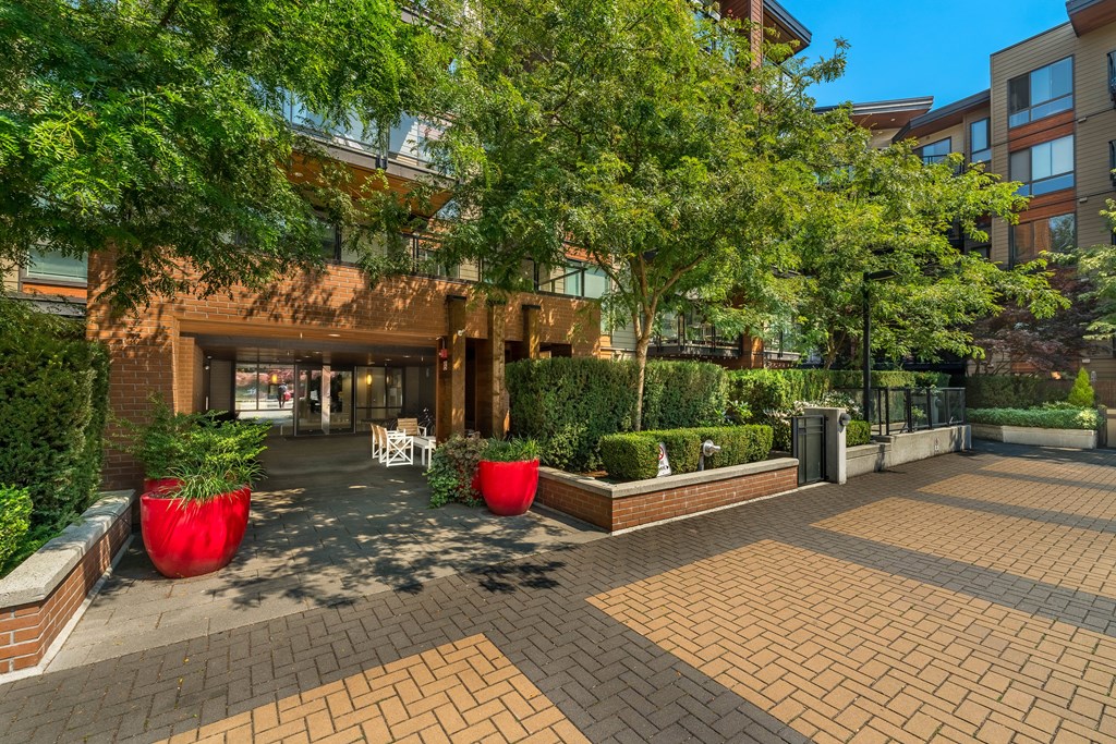 A courtyard with a building in the background and red planters in the foreground.