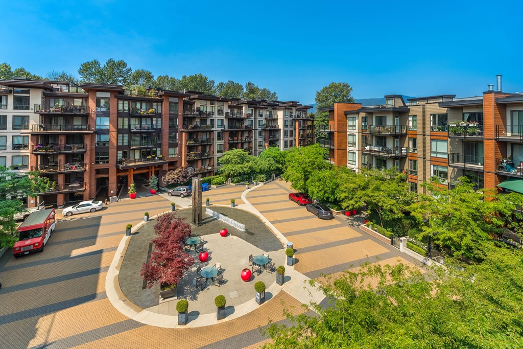 A view of a courtyard with a red car and a red bus.
