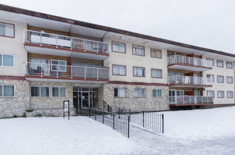 A large building with balconies and a black fence in front.