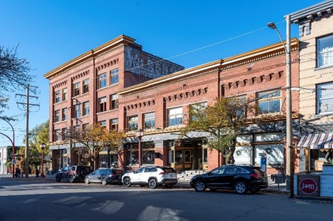A street view of a row of buildings with cars parked in front.