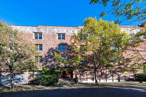 A red brick building with trees in front.