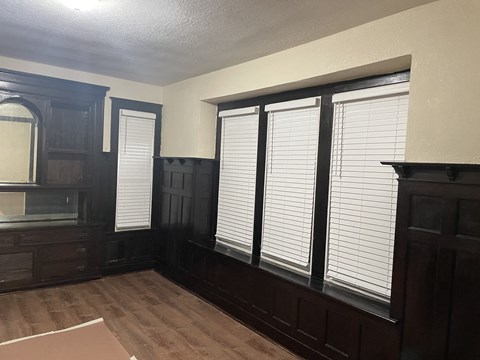 A room with wooden floors and dark brown furniture.