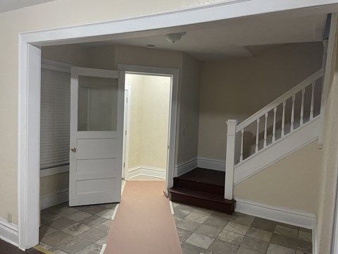 A hallway with a white door and a staircase.