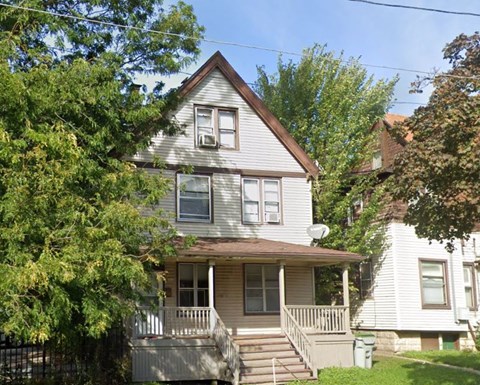 A house with a grey siding and a brown roof with a white window and a door.