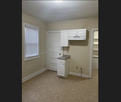 A small white kitchen with a cabinet and a counter.