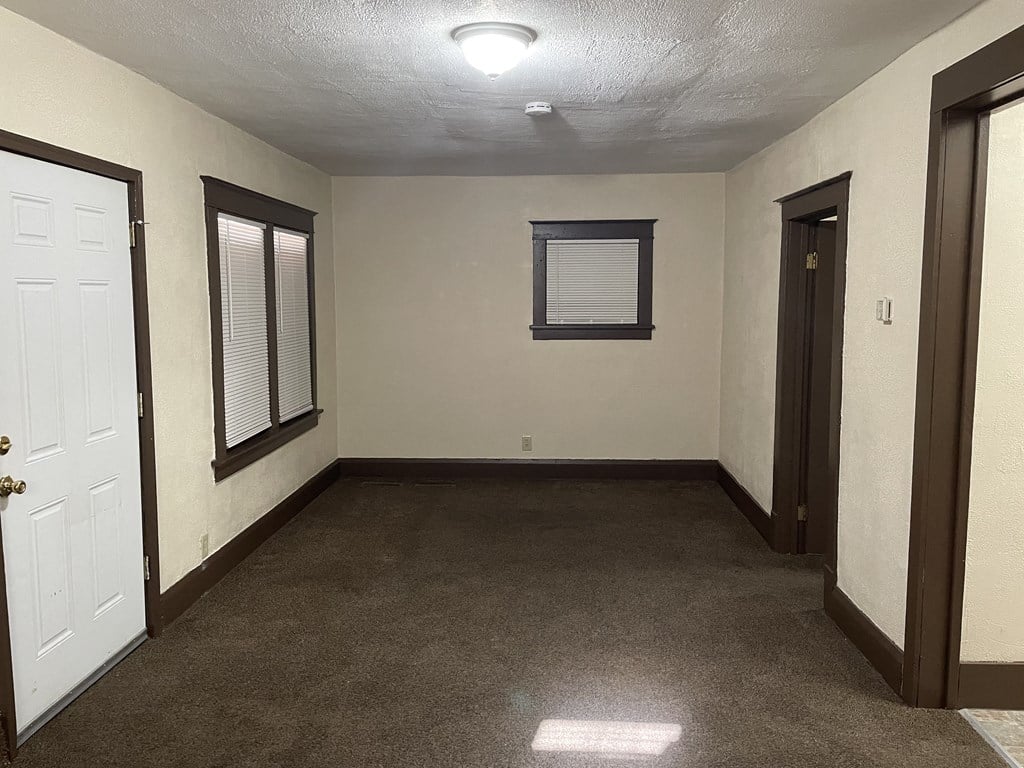 a room with a carpeted floor and two doors and a window