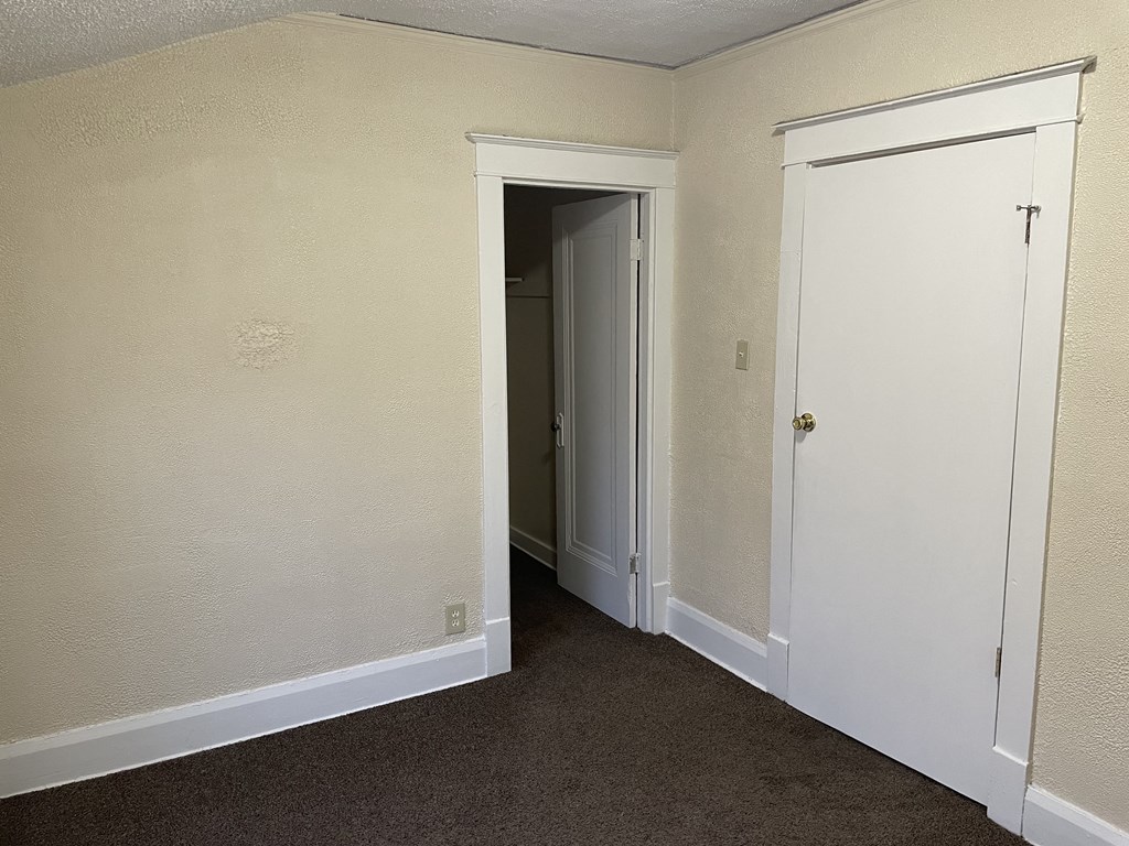 an empty room with two doors and a closet