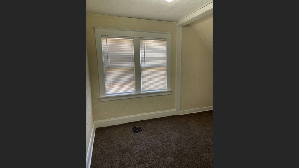 a bedroom with a window and a carpeted floor