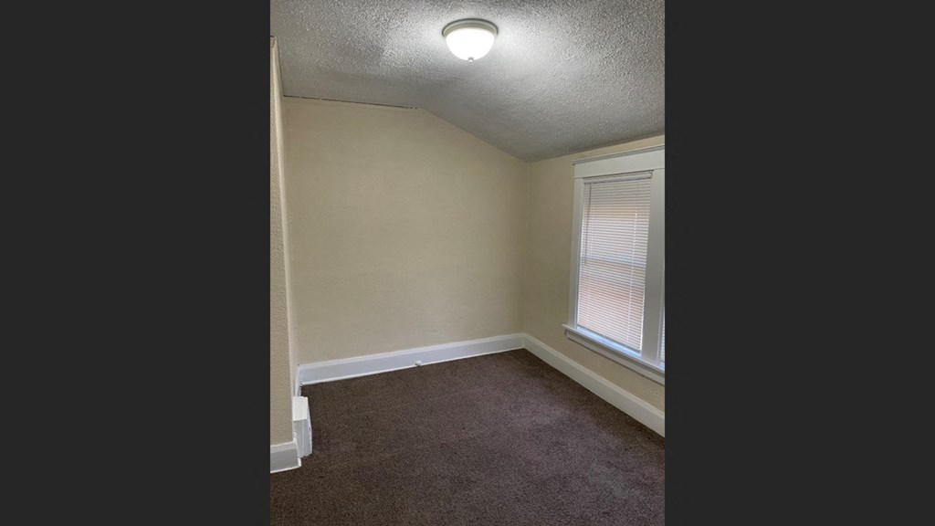 the interior of a bedroom with a window and carpet