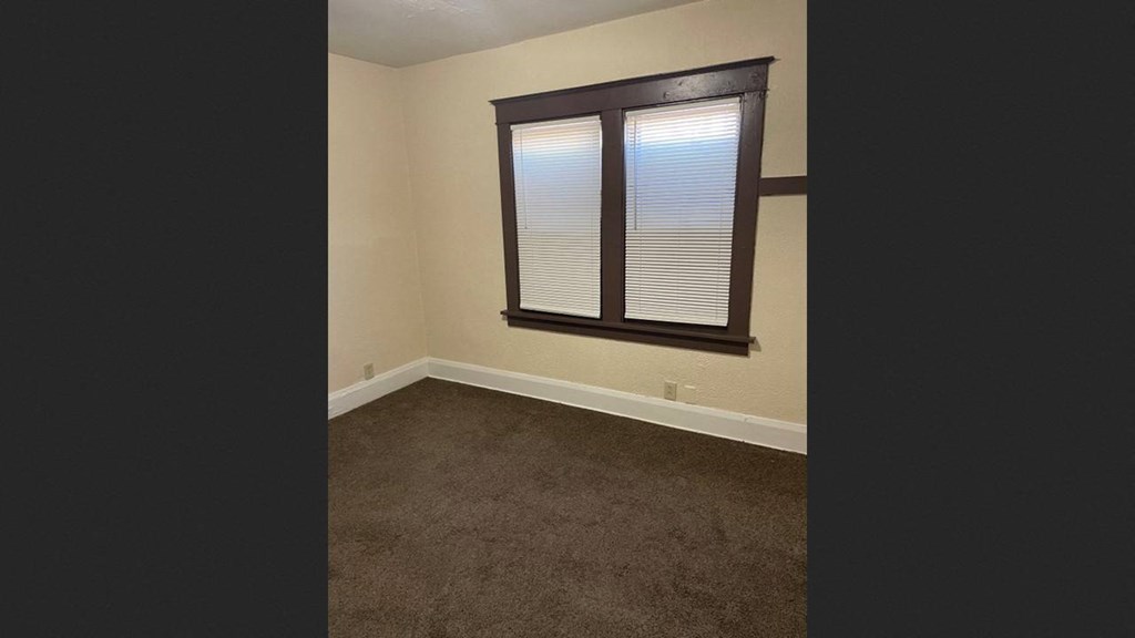 an empty room with a window and a carpet
