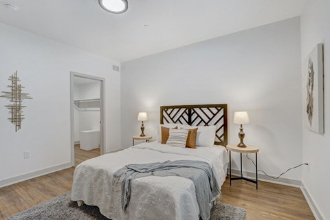 a bedroom with a bed and white walls and wood floors