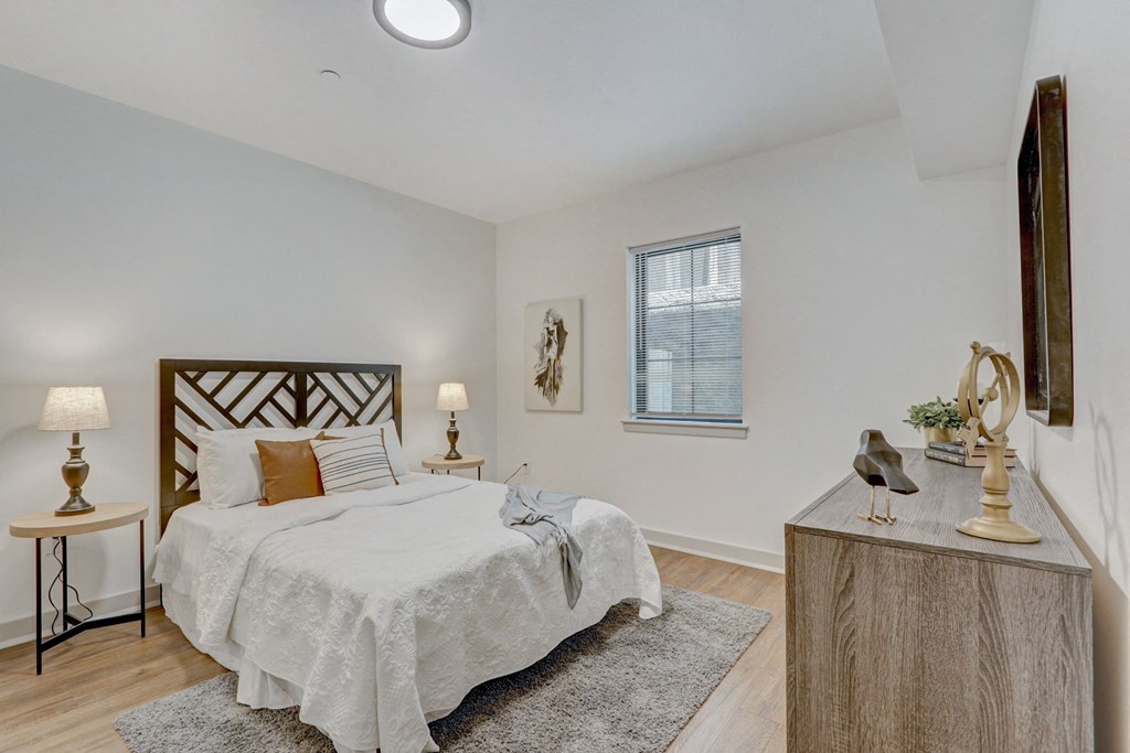 a bedroom with white walls and wood floors and a bed