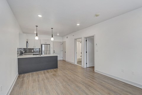 a renovated living room and kitchen with white walls and wood floors