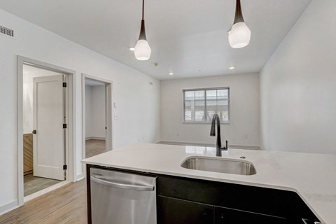 an empty kitchen with a sink and a white counter top