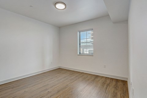 the living room of an apartment with wood flooring and a window