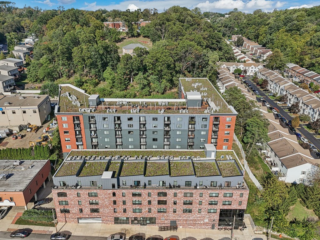 A large building with a green roof is surrounded by trees and other buildings.