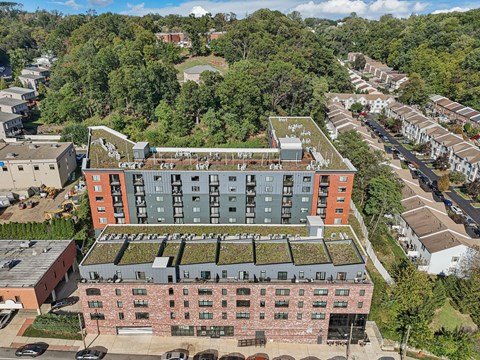 A large building with a green roof is surrounded by trees and other buildings.