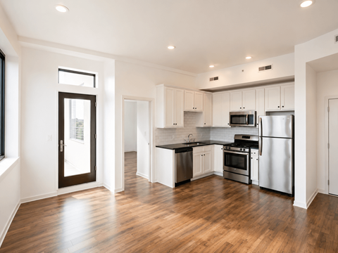 A modern kitchen with stainless steel appliances and wooden floors.