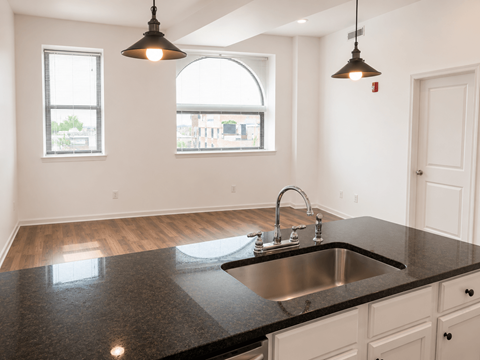A kitchen with a black countertop and a window.