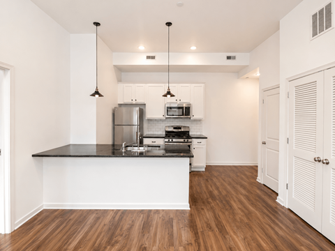 A kitchen with white cabinets and a black countertop.