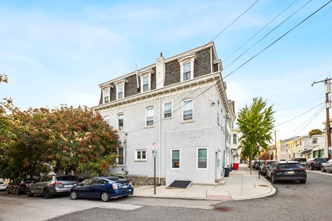 a white building with cars parked in front of it on a city street