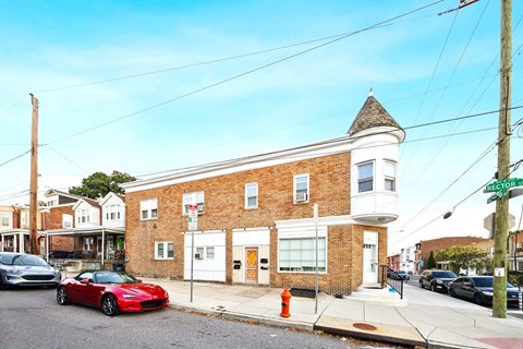 A red sports car is parked on the street in front of a brick building.