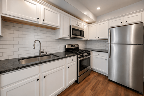 A modern kitchen with white cabinets and stainless steel appliances.