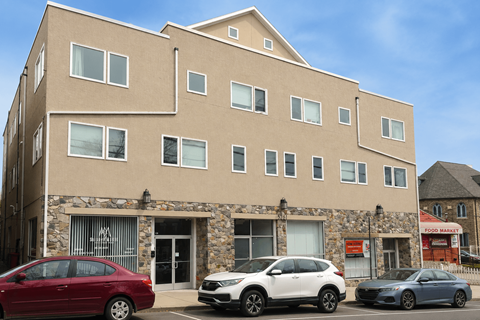 A building with a stone facade and three cars parked in front.