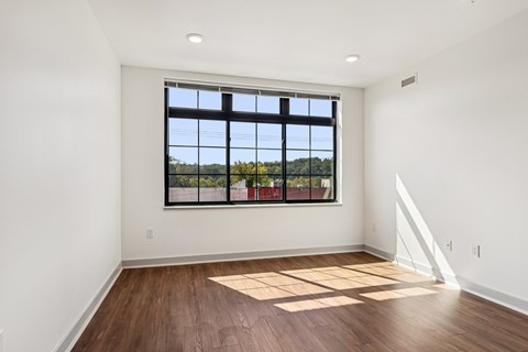 A room with a large window and wooden flooring.
