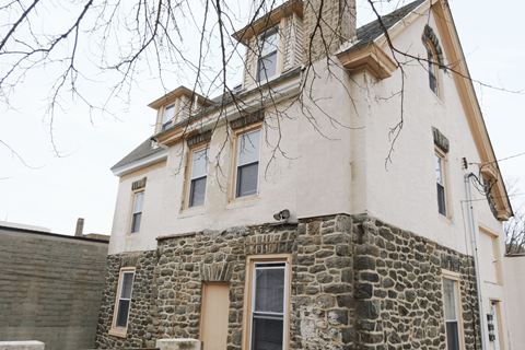 an old stone house with windows and a tree