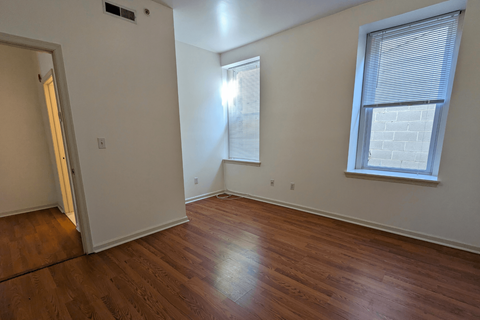 an empty living room with wood floors and two windows
