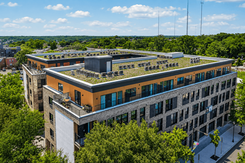 A modern building with a green roof is surrounded by trees.
