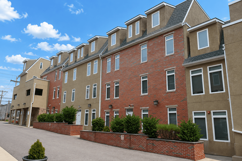 A row of red brick houses with white windows and black roofs.