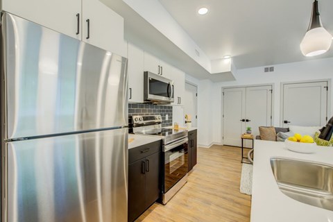 A modern kitchen with a stainless steel refrigerator and wooden flooring.