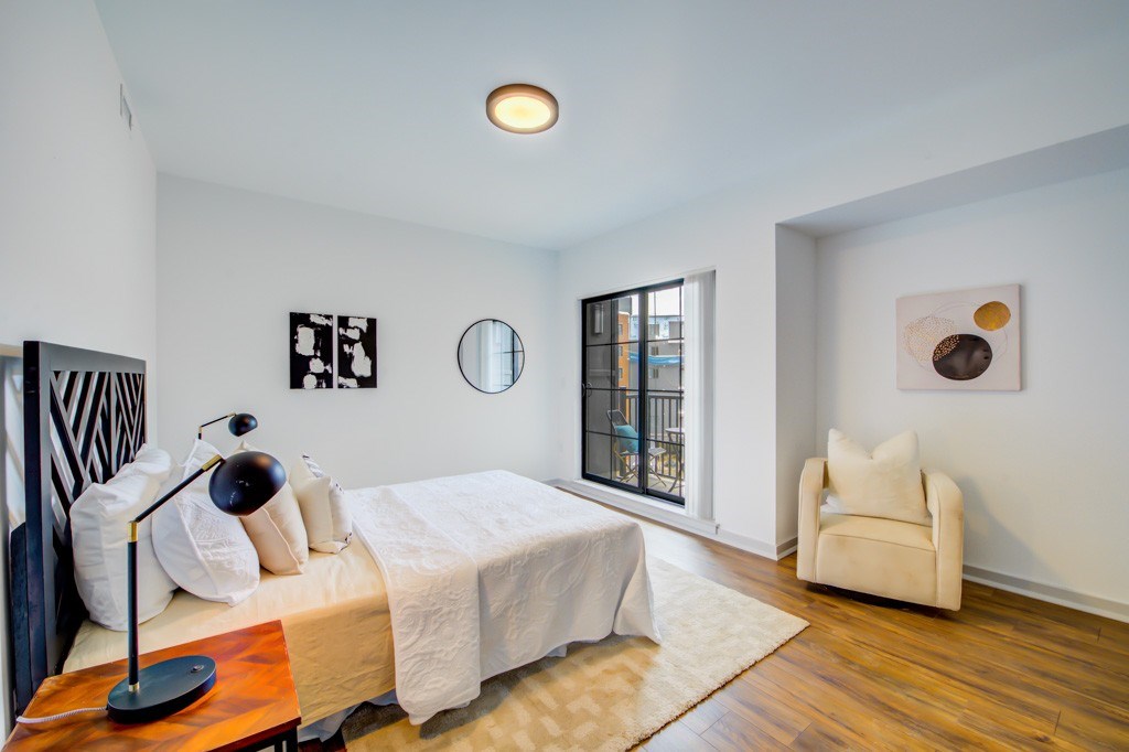 A bedroom with a bed, chair, and artwork on the wall.