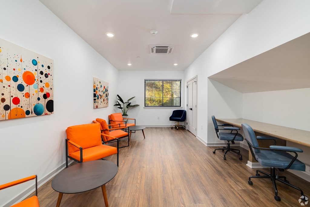 A room with orange chairs and a painting on the wall.