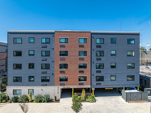 the apartment building has a red brick facade and a gray building with windows