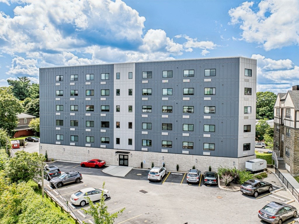 a large gray building with cars parked in a parking lot