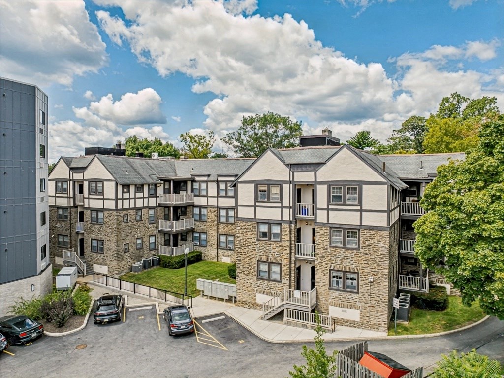 an aerial view of an apartment building with cars parked in a parking lot