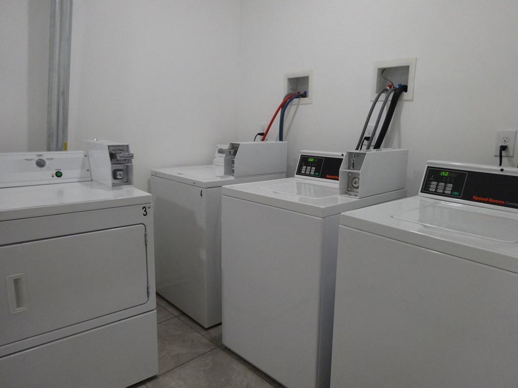 four washing machines lined up in a row in a laundry room