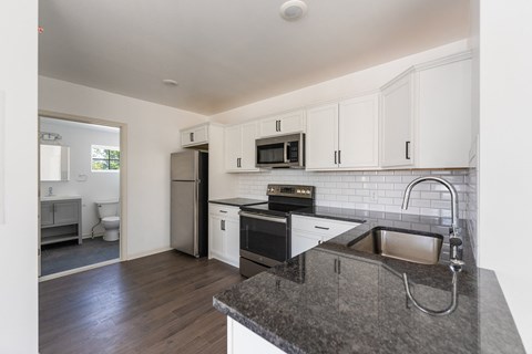 a kitchen with white cabinets and black appliances and a sink