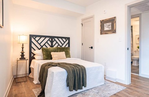 A bedroom with a white bed and a green throw blanket.