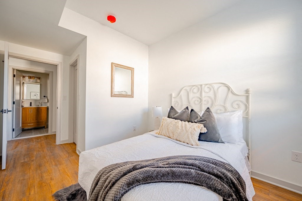 A bedroom with a white bed and a red light on the ceiling.