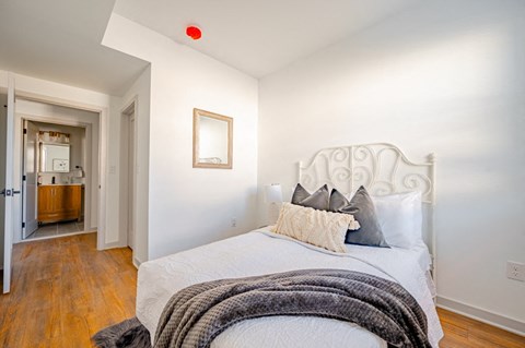 A bedroom with a white bed and a red light on the ceiling.