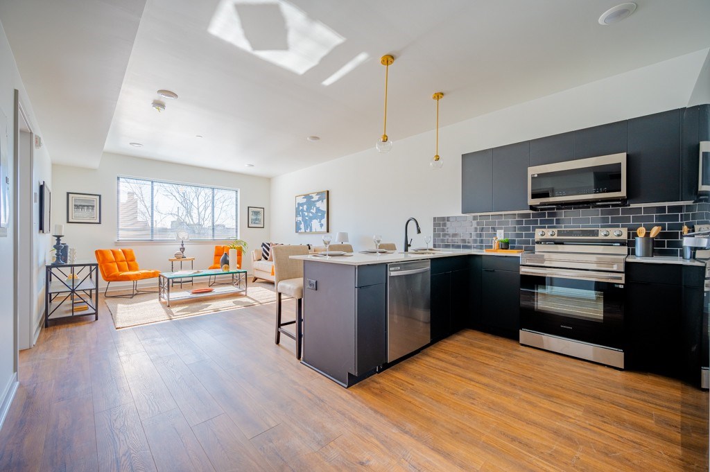 A kitchen with a black counter top and stainless steel appliances.