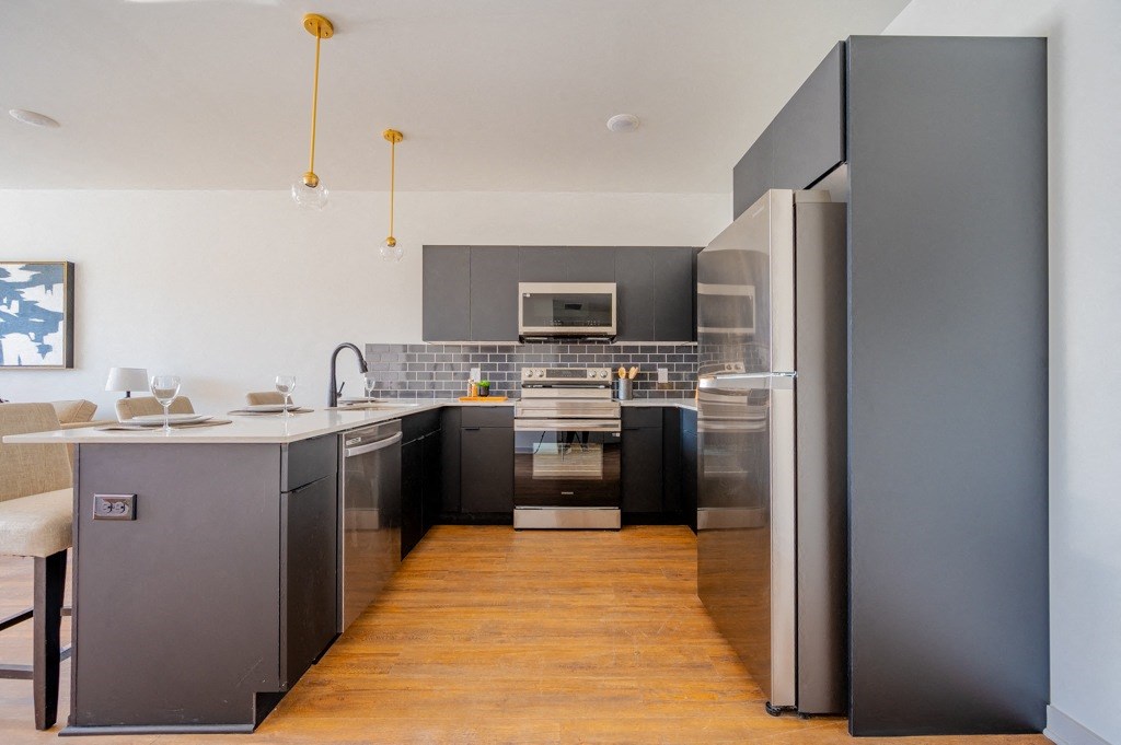 A modern kitchen with a wooden floor and grey cabinets.