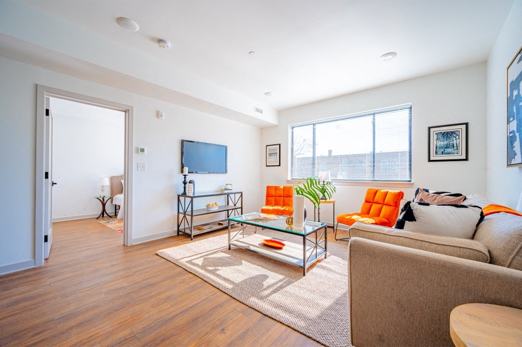 A living room with a couch, a glass coffee table, and a television.